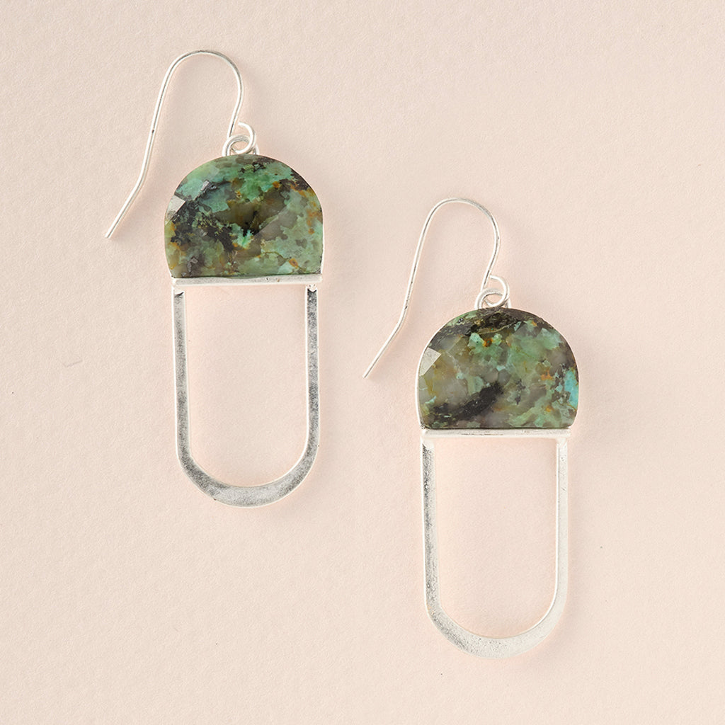 Introducing the Scout Jewelry Modern Stone Earrings, these elegant pieces showcase semi-circular green marbled stones that evoke the beauty of African Turquoise. The stones are set in silver and attached to elongated silver loops, providing both comfort and style with their hypoallergenic design free of nickel and cadmium. Displayed tastefully on a neutral background, they promise a sophisticated addition to any ensemble.