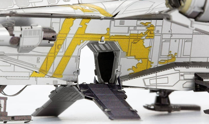 Close-up of the Mandalorian Razor Crest Star Wars Premium Metal Earth DIY model by Metal Earth, featuring a yellow and gray exterior, open cargo door with ramp to a white surface, and intricate kit-style details.