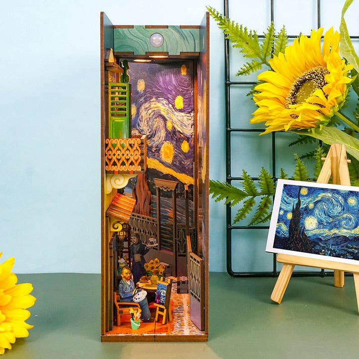 Hands Craft’s DIY Book Nook Kit: Vincent's World is a miniature diorama inspired by Van Gogh, featuring a cozy room, tiny figures, rich décor, sunflowers, and a "Starry Night" postcard for the ultimate artist-inspired bookshelf insert.