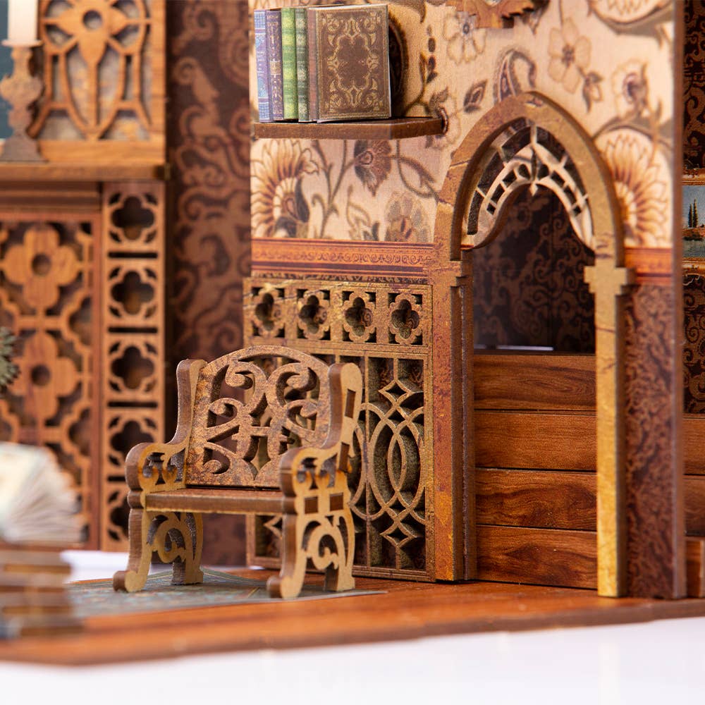 A close-up of the Hands Craft DIY Book Nook Kit: Eternal Bookstore with Dust Cover, featuring a miniature wooden bench before an ornate arched door and carved wall—an enchanting décor piece and perfect literary gift.