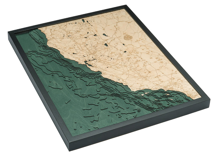 The WoodChart California Coast 24.5" x 31" Black Frame is a layered wooden map with engraved roads, towns, and water bodies. Its angled display highlights the green ocean, tan land, and detailed three-dimensional design.