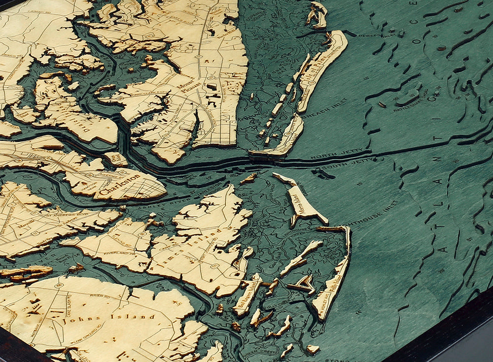 The WoodChart CharlstonSC 24.5 x 31 Black Frame is a detailed raised relief map displaying South Carolina’s coastal and island regions, featuring beige land, blue-green water, and highlighting waterways, islands, and towns.