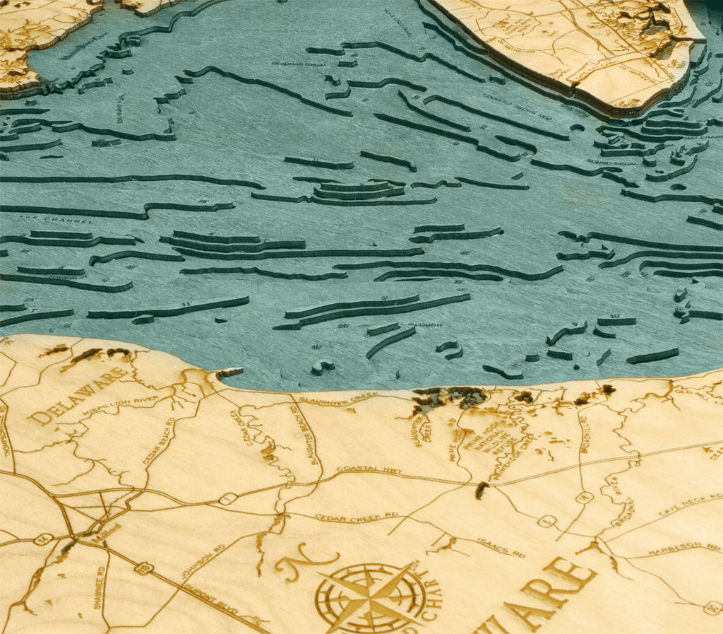 The WoodChart Deleware Bay 24.5 x 31 Black Frame is a detailed, laser-cut wooden map featuring the Delaware coastline, nearby roads, waterways, engraved labels, and topographical water depth lines.