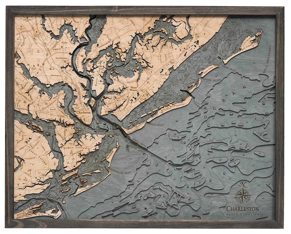The WoodChart "CharlstonSC 24.5 x 31 Grey Frame" is a wooden map of Charleston, SC, with engraved land and water details plus laser-cut layers for 3D depth. “Charleston” and a compass rose appear in the lower right corner.