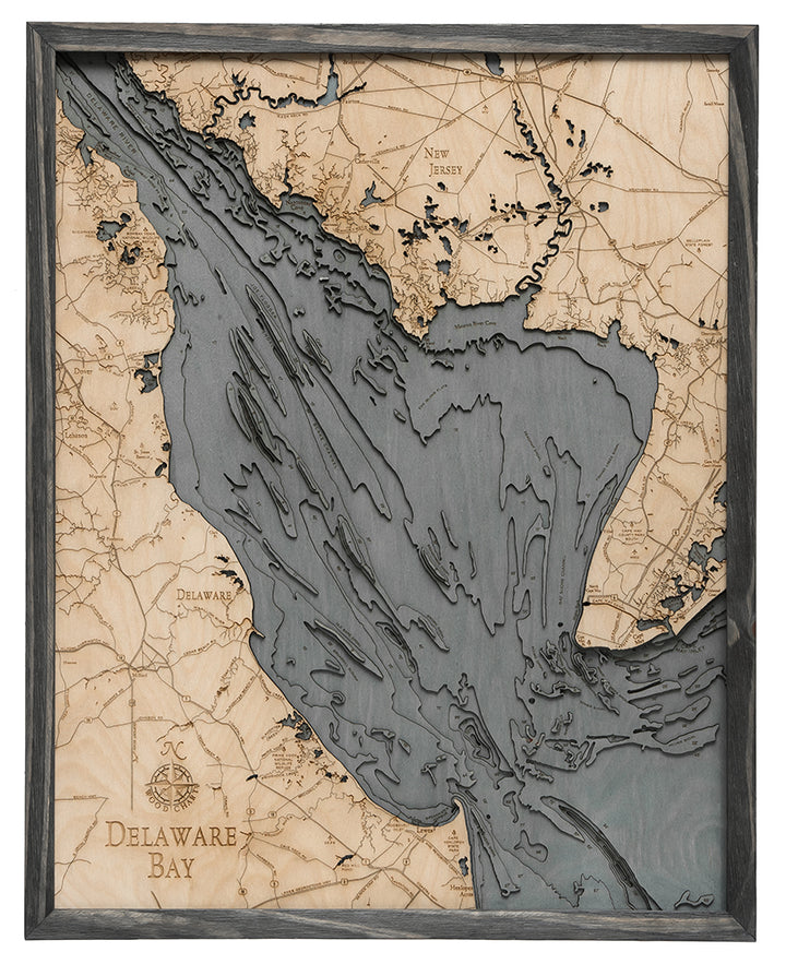 The WoodChart Deleware Bay 24.5 x 31 Grey Frame is a wooden, laser-cut map showing water depths and coastal features of Delaware Bay and nearby regions in Delaware and New Jersey, highlighted in varying shades and set in a grey frame.
