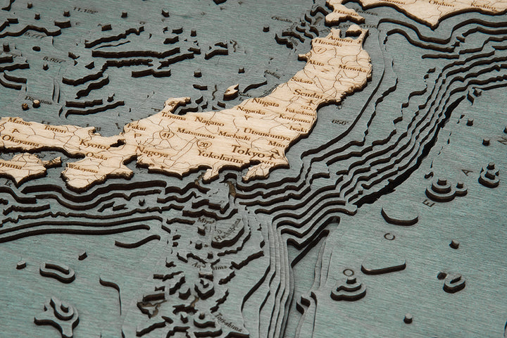 The WoodChart Japan Korea 16" x 20" Grey Frame features a detailed, layered wooden map highlighting Japan and nearby waters, with major cities like Tokyo and Yokohama labeled using raised layers for land and underwater topography.
