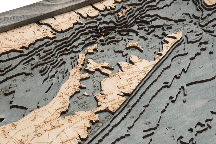 A close-up of the WoodChart Long Island Sound 13.5" x 31" map in a grey frame, featuring detailed layered wood topography, engraved place names, and surrounding waters of Long Island, New York.