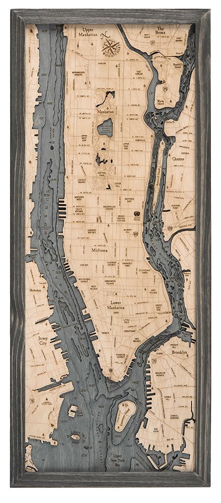 The WoodChart Manhattan 13.5" x 31" Grey Frame features an engraved wooden map of Manhattan and its surroundings, with carved rivers in darker tones and street details, all set within a sleek rectangular grey frame.