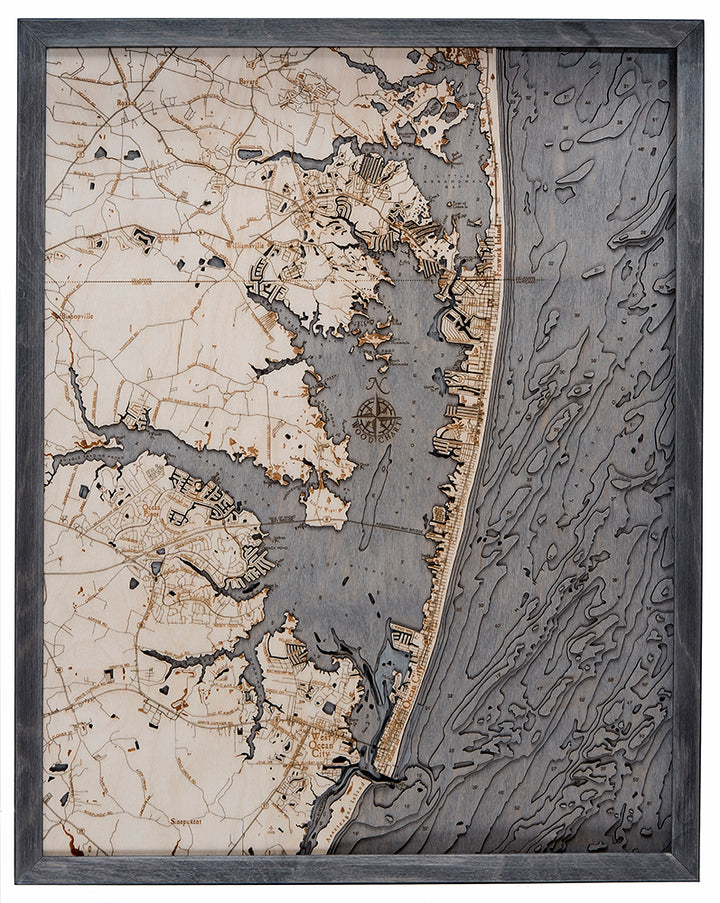 The WoodChart Ocean City MD 24.5 x 31 Grey Frame map displays detailed towns, roads, shoreline, and waterways with textured ocean patterns on the right and finely crafted city streets and buildings on land.