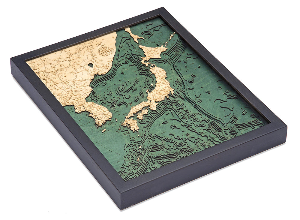 The WoodChart Japan Korea 16" x 20" Black Frame is a framed 3D topographic map of Japan and neighboring regions, with beige land, green ocean, and detailed elevation and depth contours.