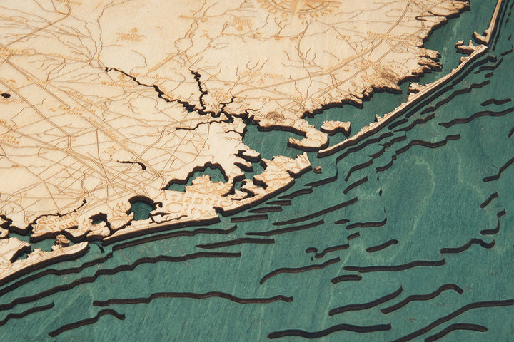 A close-up of the WoodChart Ocean City MD 24.5 x 31 Black Frame map showcases detailed laser-etched coastlines and ocean, with engraved contours and blue tones depicting the sea.