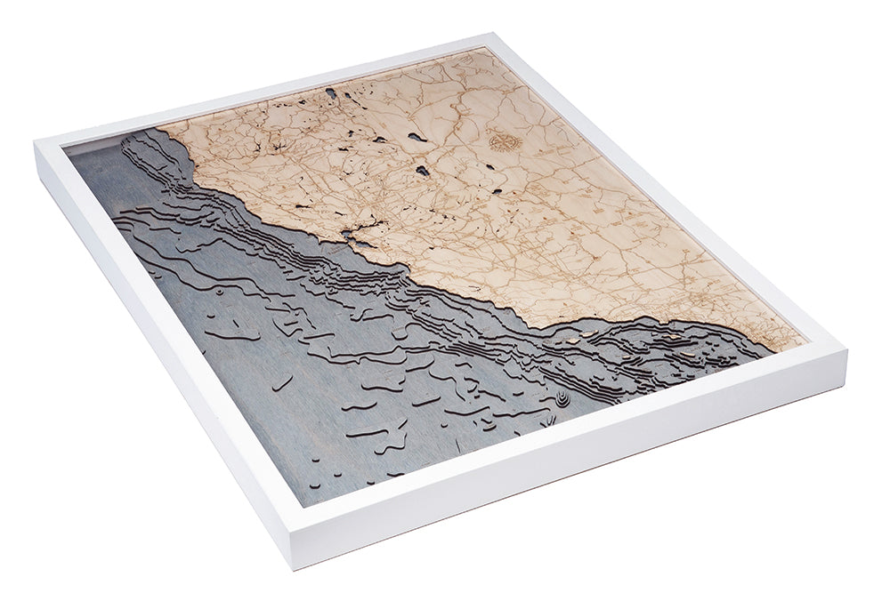 The WoodChart California Coast 24.5" x 31" White Frame is a framed, layered wooden map featuring topographic land contours and coastline details, showing the ocean in blue hues and land in neutral tones.