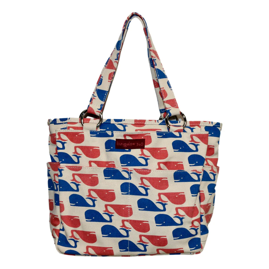 The Pocket Bag Whale by Bungalow 360 is a beige vegan canvas bag with two handles, red and blue whale silhouettes, side pockets, a polka dot lining, and a small "Bungalow 360" label on the front.
