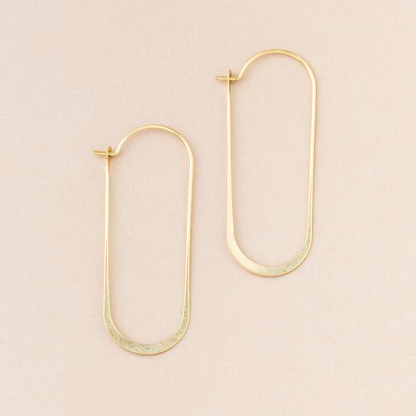 Cosmic Oval Gold earrings by Scout Jewelry are featured on a beige background. These minimalist 18K Gold Vermeil hoops have an elongated, oval design with rounded corners and are hypoallergenic, ensuring they're free from nickel and cadmium for your comfort.
