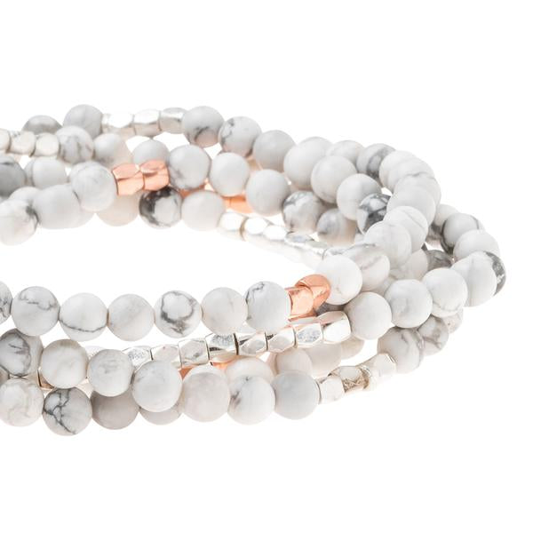 Introducing the Stone Wrap Howlite Rose Gold Silver by Scout Jewelry: a set of multi-strand bracelets crafted from round white marbled howlite stone beads intricately intertwined with small metallic beads. These bracelets elegantly wrap around each other, featuring striking silver and rose gold-toned accents, resulting in a stylish and sophisticated accessory.