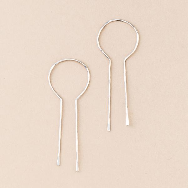 The Equinox Keyhole Hoop Silver earrings by Scout Jewelry, displayed on a beige background, showcase minimalist thin circular tops and delicate long linear drops. These hypoallergenic treasures are ideal for those desiring elegance with ultimate comfort.