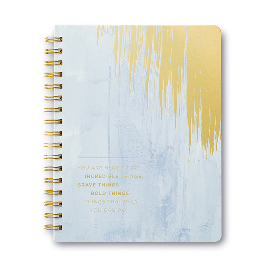 A spiral-bound notebook from Compendium, featuring a blue and gold abstract cover design with the gold text: "You are here to do incredible things, brave things, bold things, celebrating the brilliance that only you can bring.