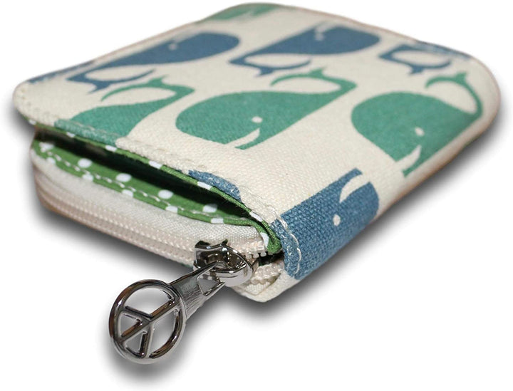 The Bill Fold Wallet Whale by Bungalow 360 features a blue and green whale pattern on beige fabric, with a silver peace sign pull. It’s partially open, revealing an eco-friendly green and white polka dot interior.