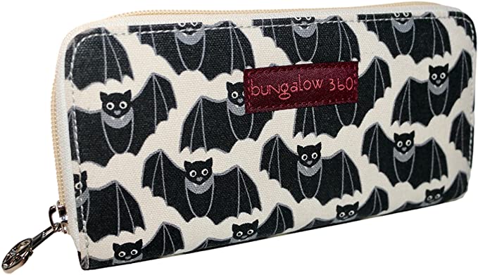 Introducing the Bungalow 360 Zipper Wallet Bat: crafted from cotton canvas, this wallet showcases a unique pattern of smiling black bats set against a cream background. Ideal for animal and pet enthusiasts, it is accented with a red label bearing white text on the front.