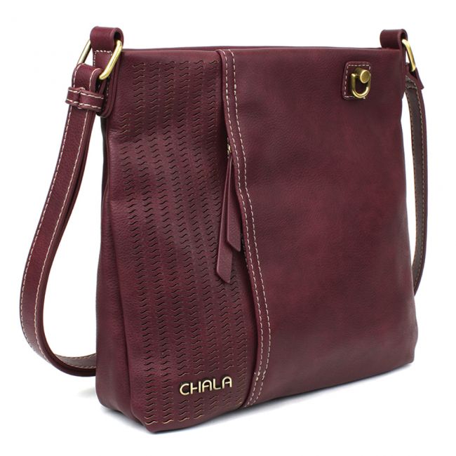 Introducing the Chala Lasercut Crossbody DF in plum—a stylish shoulder bag crafted from faux leather. It features an adjustable strap and decorative stitching on one side, complemented by gold-tone hardware. The front pocket showcases a laser-cut pattern, with logo detailing located at the bottom left corner for a signature finish.