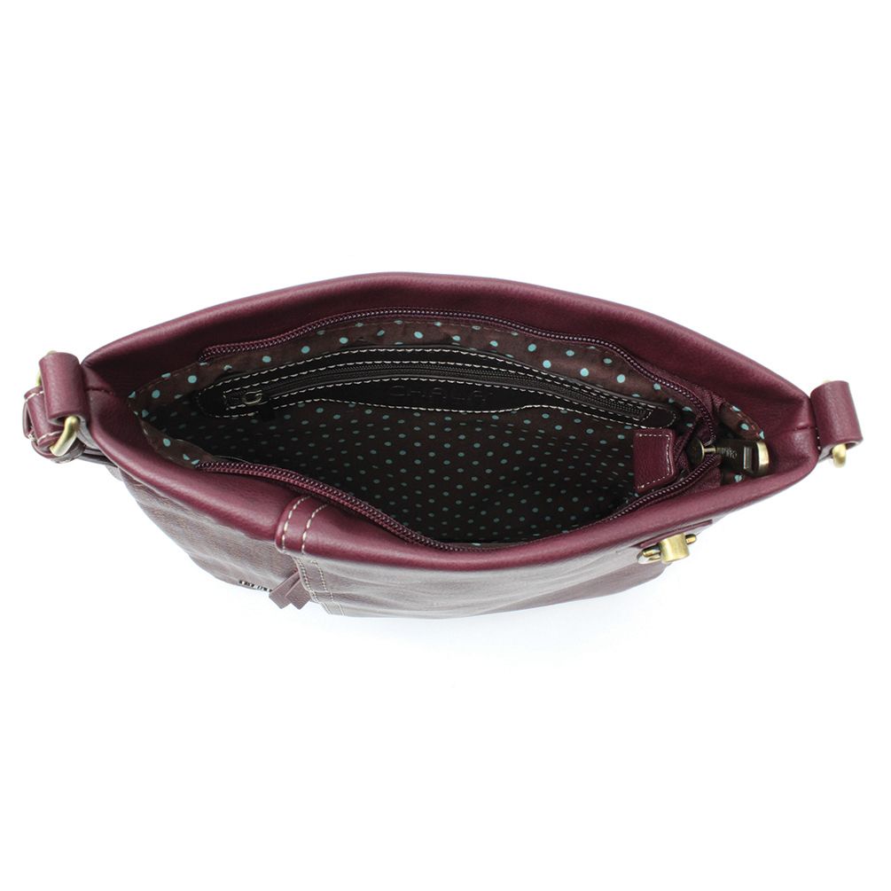 The Lasercut Crossbody DF in plum by Chala reveals a chic interior lined in black fabric with white polka dots when opened. From above, a zipper pocket and main compartment are visible. The gold-tone hardware accents on the strap connections, along with adjustable straps, ensure a perfect fit for style on the go.