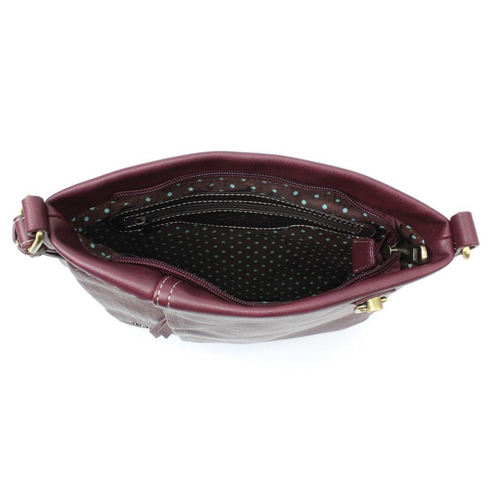 The Lasercut Crossbody DF in plum by Chala reveals a chic interior lined in black fabric with white polka dots when opened. From above, a zipper pocket and main compartment are visible. The gold-tone hardware accents on the strap connections, along with adjustable straps, ensure a perfect fit for style on the go.