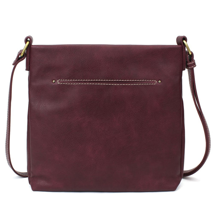 Introducing the Lasercut Crossbody DF in plum by Chala, a faux leather crossbody bag with a minimalist design. This bag offers a sleek, rectangular shape, a slim front pocket accented with white stitching, and adjustable straps featuring elegant brass hardware.