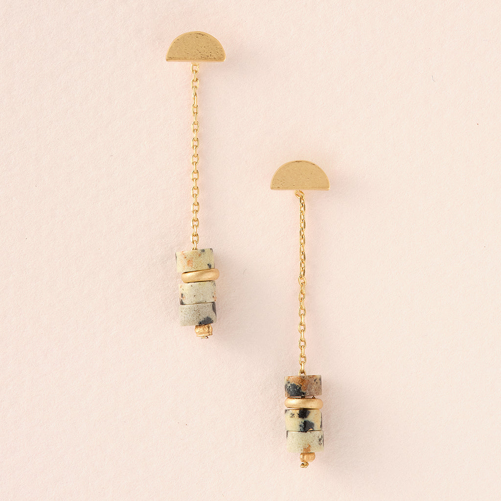 The Meteor Thread Dalmation Jasper Gold earrings by Scout Jewelry feature two gold half-circles connected by chains and cylindrical stone accents with marbled gold-banded stones. Made from nickel and cadmium-free materials, these hypoallergenic earrings guarantee elegance and comfort.