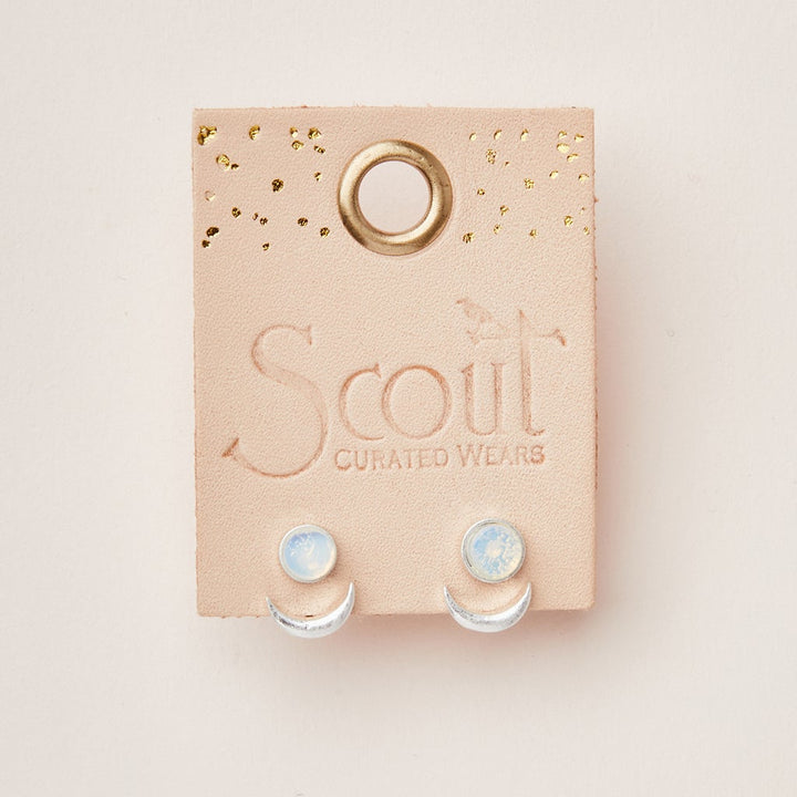 A pair of hypoallergenic Moon Phase Opalite/Silver earrings from Scout Jewelry is presented on a light pink card embossed with the brand's name. The card includes a circular hole at the top and gold-speckled accents, making these versatile beauties as gentle on your ears as they are stunning.