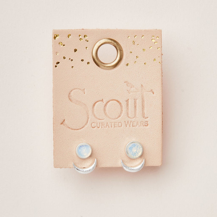 A pair of hypoallergenic Moon Phase Opalite/Silver earrings from Scout Jewelry is presented on a light pink card embossed with the brand's name. The card includes a circular hole at the top and gold-speckled accents, making these versatile beauties as gentle on your ears as they are stunning.