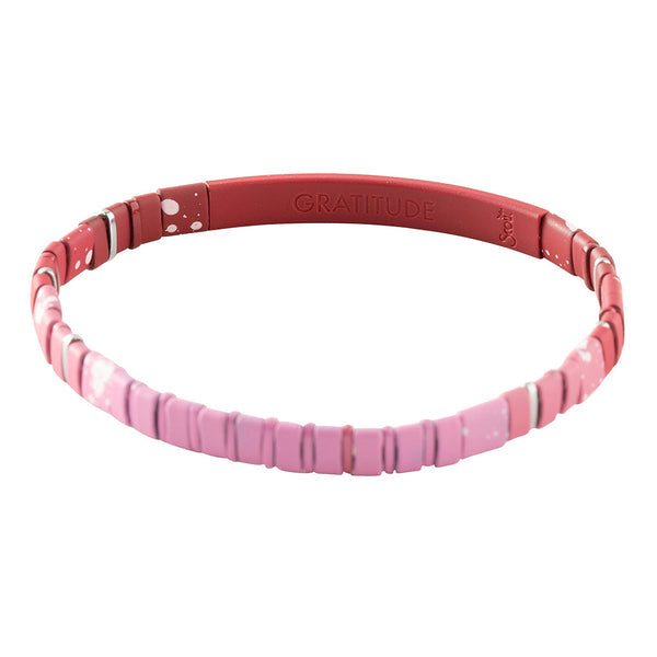 A close-up image of the Good Karma Ombre Gratitude Mulberry Silver bracelet by Scout Jewelry shows its stunning red and pink design. The beaded bracelet, part of the Good Karma collection, features an engraved "GRATITUDE" message on the red band segment. Alternating small flat pink beads with white spacer beads create a colorful and stylish accessory that embodies empowerment.