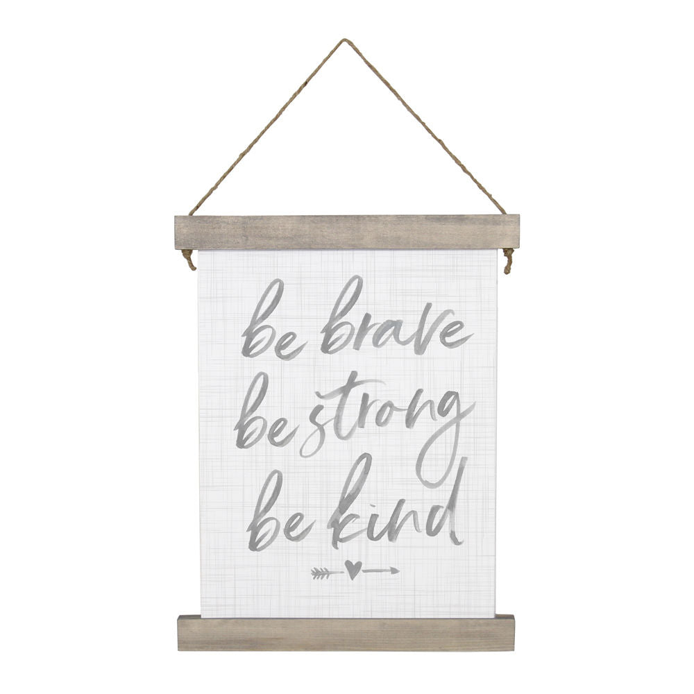 The "Be Brave" wall hanging by SincereSurroundings features handwritten phrases "be brave, be strong, be kind" in gray on a light grid background. It is framed with stained wood and hangs from a simple rope, with a small arrow and heart adorning the design.