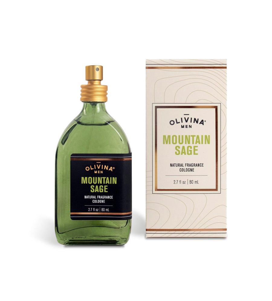 A green bottle of Barrel and Oak Mountain Sage Cologne (2.7 fl oz) is shown next to its matching beige and green box. The bottle has a gold spray cap, and the label features the brand name and scent in green, black, and gold colors, highlighting its essential oil-based fragrance.