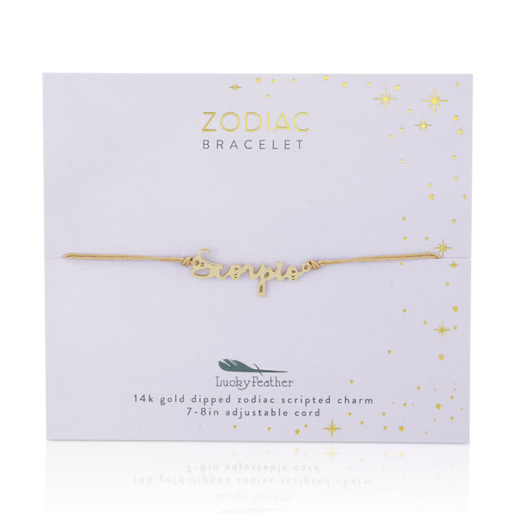 The Zodiac Bracelet Scorpio from LuckyFeather, featuring a 14k gold-dipped scripted charm spelling "Scorpio," is displayed against a white background. The packaging, adorned with star and constellation illustrations, reads "Zodiac Bracelets" and "Lucky Feather." The adjustable, nickel-free cord ranges from 7-8 inches.