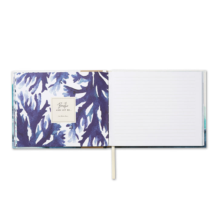 An open Swept Away Coastal Guest Book by Compendium displays a page with blue abstract floral patterns on the left and lined writing space on the right, making it ideal for capturing meaningful moments. A ribbon bookmark rests in the center, ready to guide you through everyday joys.