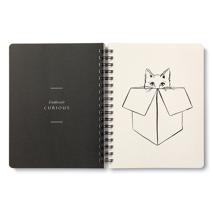 A Wild at heart Spiral Notebook by Compendium with a black cover displaying the text "Endlessly CURIOUS" on the left-hand side. The right-hand page showcases a minimalistic, black line drawing of a cat peeking out from inside a cardboard box—ideal for animal lovers and admirers of whimsical cat illustrations.