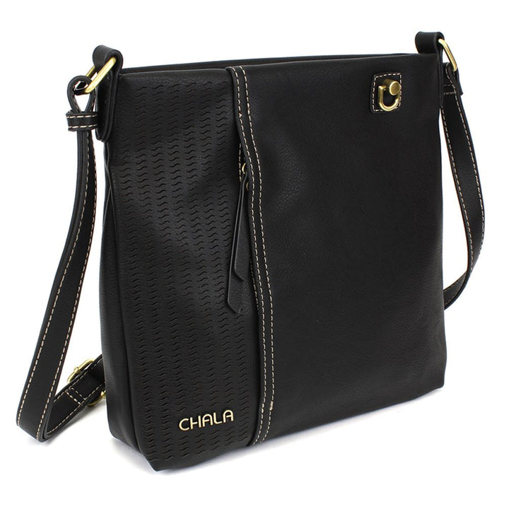 The Lasercut Crossbody DF Black by Chala is a striking black shoulder bag that showcases a textured panel and intricate laser cut pattern on the left side. The edges are accentuated with contrasting white stitching, while the adjustable straps are adorned with a gold buckle and decorative grommet. "CHALA" is elegantly embossed in gold at the bottom left corner of this faux leather accessory.