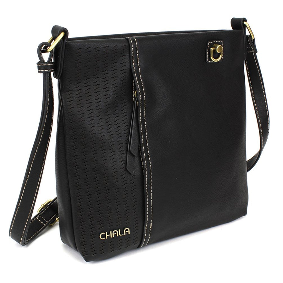The Lasercut Crossbody DF Black by Chala is a striking black shoulder bag that showcases a textured panel and intricate laser cut pattern on the left side. The edges are accentuated with contrasting white stitching, while the adjustable straps are adorned with a gold buckle and decorative grommet. "CHALA" is elegantly embossed in gold at the bottom left corner of this faux leather accessory.