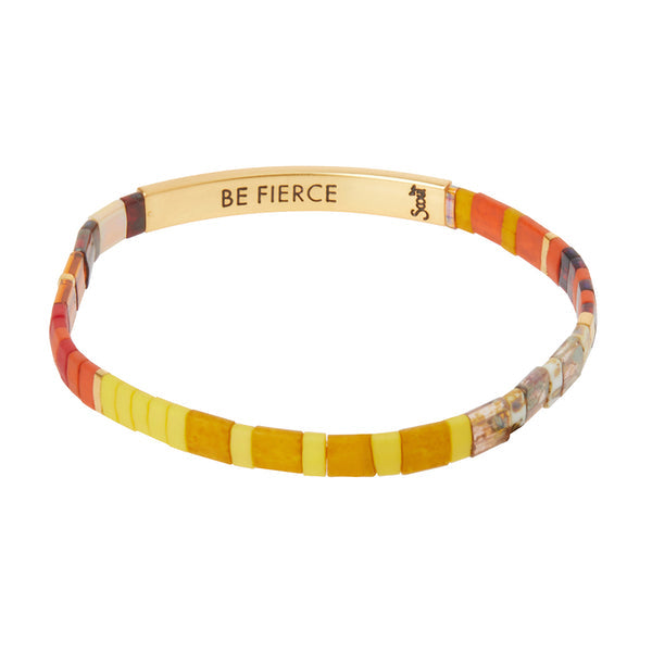 The Miyuki Be Fierce Sunset Gold bracelet by Scout Jewelry showcases vibrant yellow, orange, and red beads with a 14K gold-dipped bar inscribed with "BE FIERCE.